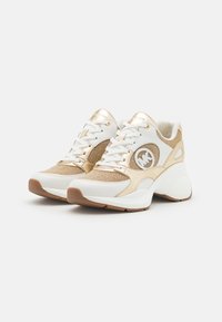 Bílé a zlaté tenisky vyrobené z technické síťoviny a kůže, s kulatou špičkou, silnou gumovou podrážkou a logem na boku.