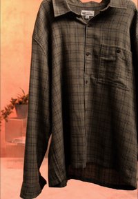 Chemise à carreaux marron à manches longues, boutonnée, suspendue, avec une poche poitrine et une étiquette de marque GAP sur le col.