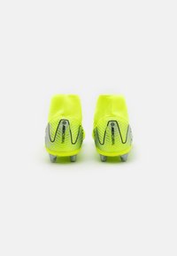 Des crampons de football jaune vif au design montanth, avec des accents gris et une surface texturée. Des crampons argentés offrent une traction.