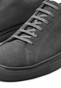 Gray suede shoes with lace-up design, featuring a textured rubber sole and tonal stitching throughout. Smooth finish and minimalistic style.