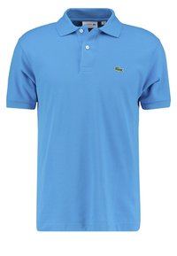 Ljusblå polo-shirt i bomull med texturerad yta, med klassisk krage och en grön krokodil-logotyp på vänster bröst.