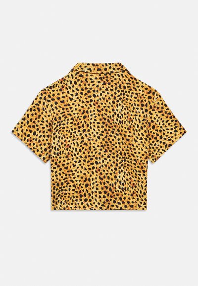 Košulja kratkih rukava s ovratnikom od žutog tkanja s uzorkom leoparda koji se sastoji od crnih i smeđih mrlja na cijeloj površini.