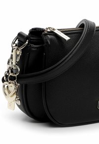 Czarna skórzana torba na ramię o fakturowanej powierzchni, wyposażona w zamek błyskawiczny, srebrne okucia oraz akcenty w postaci breloków.
