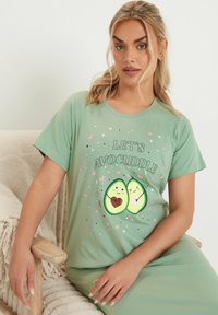Grön bomullsnattlinne med en avokado-illustration med hjärtan och texten "Låt oss avokuddla", rund halsringning och korta ärmar.