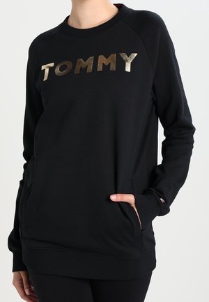 Zwarte trui met ronde hals, voorzien van een gouden "TOMMY" print. Het heeft lange mouwen en zijzakken, met ribgebreide cuffs en onderkant.