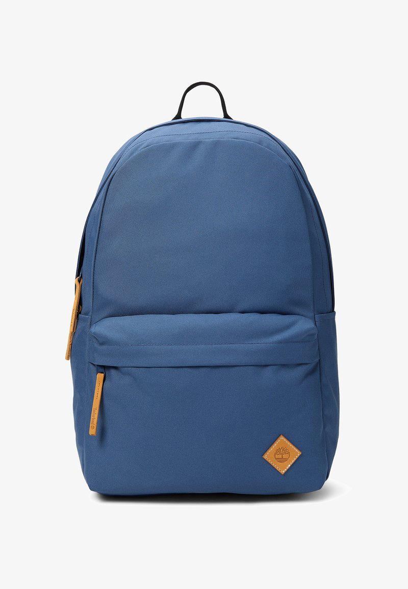 Blauwe rugzak met een voorvak met ritssluiting, zwarte bovenhandgreep en een klein bruin leren label met een boomlogo in de rechterbenedenhoek.