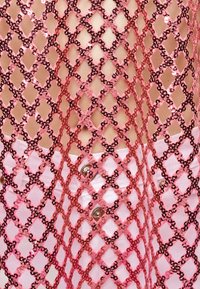 Ρόζ υφασμάτινο δίχτυ με παγιέτες, απλωμένο πάνω σε γυμνό δέρμα και λευκό παντελόνι με μεταλλικά κουμπιά, δημιουργώντας ένα αντιθετικό υφασμάτινο μοτίβο.