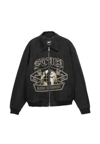 Čierna bundy na zips s golierom, vyšitým globom a bannerom s nápisom "Od roku 1991 Globálny turnaj" v béžovej farbe na prednej strane.