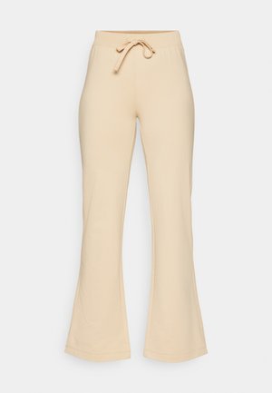 Pantalons de survêtement beige évasés avec taille à cordon, fabriqués en tissu doux, présentant une texture lisse et des coutures minimales.