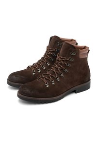 Un par de botas de senderismo de ante marrón oscuro con cuellos acolchados y ojetes de metal, cordoneras de color marrón y amarillo con un patrón.
