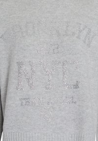 Gray pullover sweater featuring rhinestone embellishments with text: "BROOKLYN 1972 NYC TEAM AUREL" and a heart graphic at the bottom.