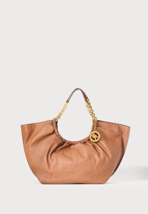 Sac cabas en cuir marron avec haut froncé, anses en chaîne dorée et breloque ronde dorée avec logo suspendue près de la fixation de la anse.