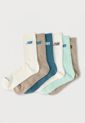 Six paires de chaussettes montantes côtelées en blanc, beige, bleu sarcelle et menthe, chacune arborant le logo New Balance près du haut.