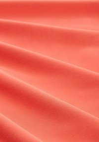 Coral fabric with a smooth texture, featuring soft drapes and a uniform surface. The color is bright and vibrant, suitable for various uses.