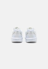 Baskets de sport blanches avec une surface lisse, des accents en maille et une semelle rembourrée. Présentent un logo à l'arrière et une sangle de tirage pour un enfilage facile.