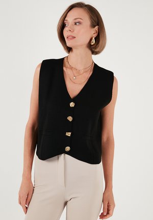 Black sleeveless vest with a V-neck, featuring five gold buttons, two front pockets, and a cropped hemline. Smooth, structured fabric.