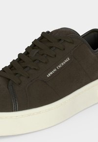 Καφέ καστόρινο sneaker Armani Exchange με μαύρα κορδόνια και λευκή καουτσούκ σόλα, που δείχνει το πλαϊνό λογότυπο και λεπτομέρειες ραφής.