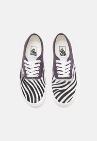 Vans obuća s materijalom u crno-bijelim prugama, s tamnoljubičastim platnenim gornjim dijelom i bijelim vezicama.