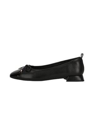 Ballerine plate noire à petit talon avec bout pointu brillant, petit nœud avec embouts métalliques sur le devant, et languette à l'arrière du talon.