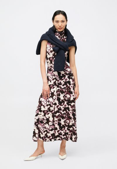 Μίντι φόρεμα με ανθικό σχέδιο σε σκούρες αποχρώσεις με ροζ και λευκά σχέδια, κατασκευασμένο από απαλό ύφασμα. Συνδυάζεται με σκούρο πλεκτό κασκόλ και άνετα παπούτσια slip-on.