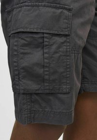 Shorts cargo gris avec plusieurs poches, une texture de tissu douce et des détails de couture visibles sur l'ourlet et les rabats de poche.