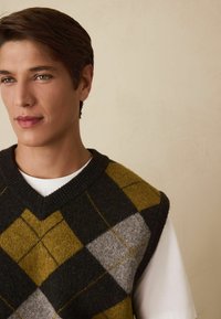 Gestrickter ärmelloser Pullover mit Rautenmuster in Dunkelgrau, Olivgrün und Hellgrau, mit tiefem V-Ausschnitt und geripptem Kragen.