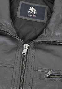 Gray leather jacket featuring a quilted interior, silver zippers, and an interior label with "OTTO KERN" and a lion logo.