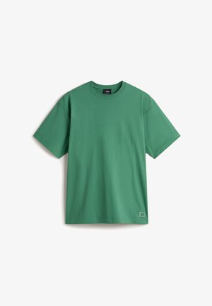 Grünes Kurzarm-T-Shirt aus Baumwolle mit Rundhalsausschnitt, lockerer Passform und einem kleinen Logolabel an der unteren Seite.