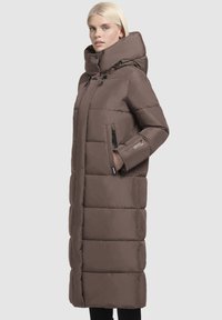 Dolga rjava puhastna jakna z visokim ovratnikom, zadrgo na žepih, prešitimi detajli in rahlo sijočo teksturo. Ima ravno silhueto.