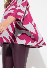 Top grigio con audace motivo astratto fucsia e bianco, maniche a campana, abbinato a leggings attillati bordeaux, texture liscia.