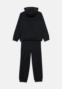 Survêtement noir comprenant une veste à capuche avec zip et un pantalon élastiqué. Fabriqué en tissu doux avec des poignets et une taille côtelés.