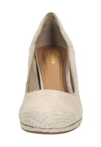 Chaussure à talon haut beige avec un design en simili-cuir serpent texturé, bout rond et profil latéral découpé. Elle possède une doublure intérieure douce.