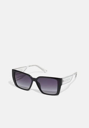 Black rectangular sunglasses with gradient lenses, clear side arms featuring logo accents, and a thick frame design.