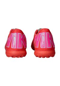 Rde čevlje za šport z gladkim zgornjim delom, velikim logotipom "NIKE" v roza in beli barvi ter teksturiranim gumijastim podplatom za oprijem.