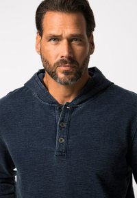 Mörkblå hoodie med henley-design och tre mörka knappar, tillverkad av texturerad tyg, med avslappnad passform och subtilt mönster.