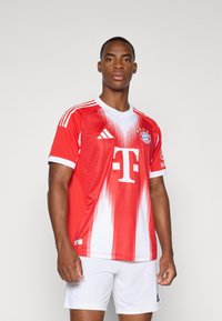 Rød og hvit Adidas-drakt med gradientdesign, rund hals, laglogo og sponsorlogo på forsiden; lett stoff.