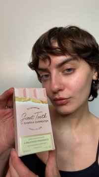 Różowe pudełko na perfumy ze złotym akcentem i tłoczonym napisem. Etykieta z napisem "Sweet Tooth by Sabrina Carpenter", 30 ml, podkreślona zielonym opisem.