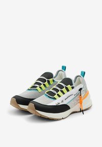 Zapatillas de correr tecnológicas con una parte superior de textil mixto en gris y negro, detalles en verde neón y una llamativa cinta de tira en naranja.