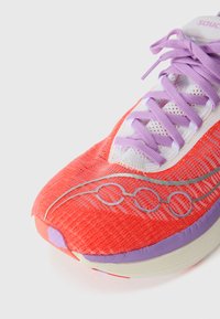 Baskets de course rouges et violettes avec un dessus en mailles texturées, un design d'accent en argent et une semelle légèrement rembourrée. Lacets en violet clair.