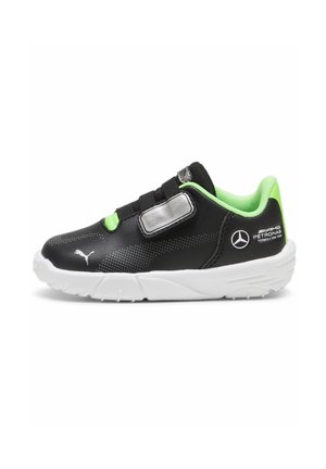 Black children's sneaker with green accents, synthetic material, elastic strap, textured surface, and white rubber sole. Features brand logos.