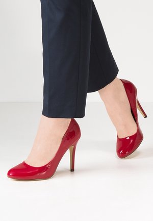 Czerwone lakierowane szpilki z zaokrąglonym noskiem i smukłym obcasem typu stiletto. But posiada błyszczące wykończenie i gładką teksturę.