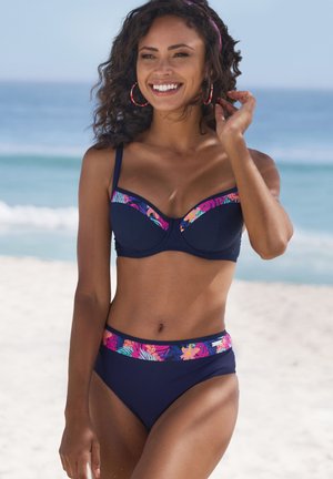 Marineblauer Bikini mit einem blumengemusterten Band; das Oberteil hat eine Unterdrahtunterstützung und verstellbare Träger, während der hoch taillierte Slip zusätzlichen Schutz bietet.