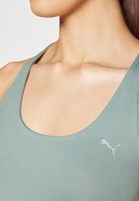 En lys grønn sports tanktop med scoop hals, laget av glatt stoff, med en liten hvit Puma-logo på brystområdet.