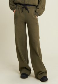 Pantalones deportivos verde oliva con un corte relajado, que cuentan con una cintura elástica con cordón, bolsillos laterales y puños acanalados.