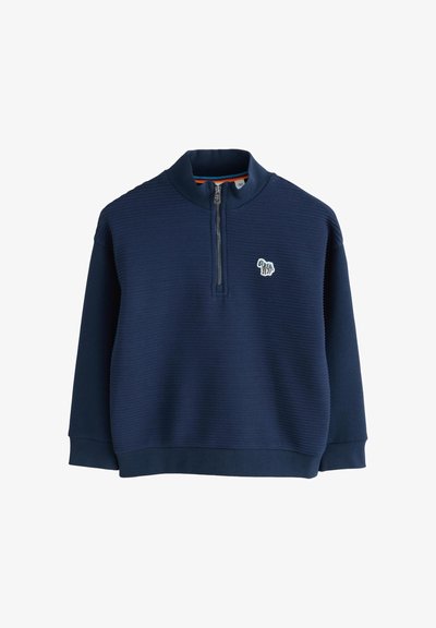 Tumši zilas krāsas sporta krekls ar rāvējslēdzēju, izgatavots no teksturētas auduma. Tajā ir viltus apkakle un krāsains iekšējais oderējums, ar nelielu izšūtu dizainu krūtīs.