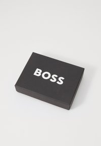 Black rectangular box featuring a white "BOSS" logo on the top, made of textured cardboard. Minimalist design, no additional patterns or accents.