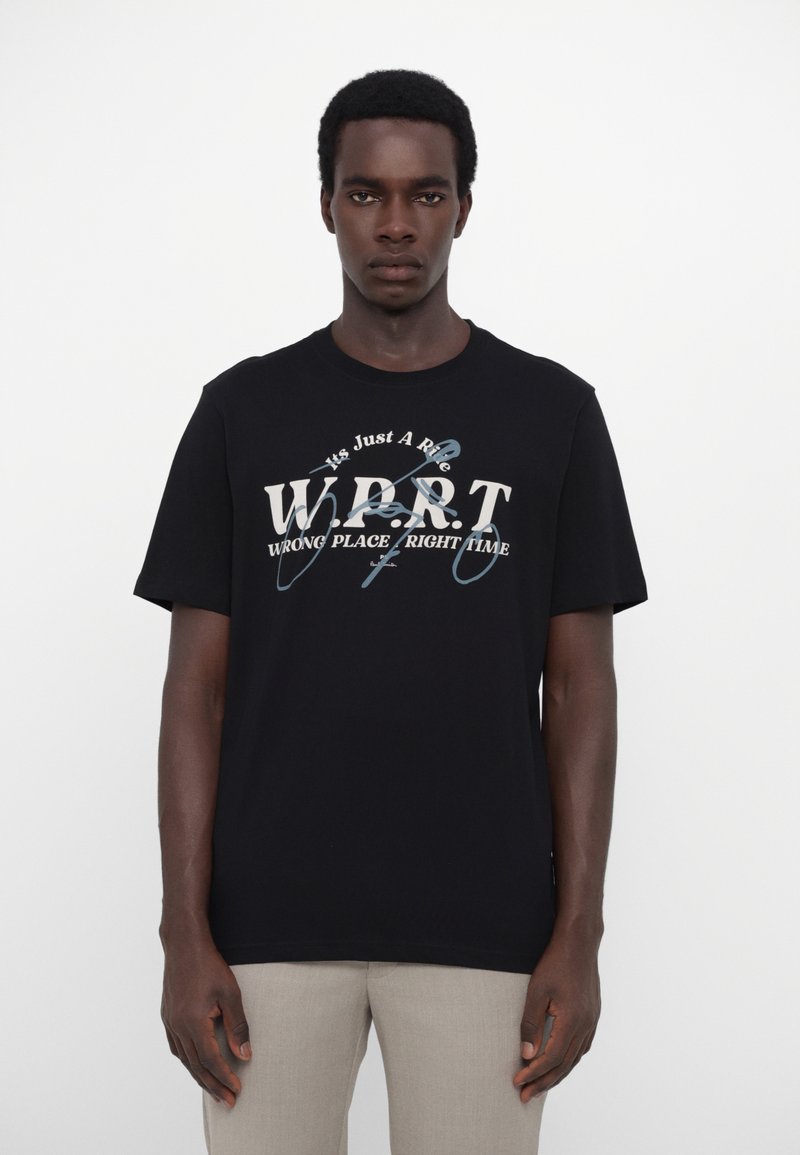Tricou din bumbac negru cu mâneci scurte, având un design de text alb și albastru "W.P.R.T. Wrong Place Right Time" pe piept.