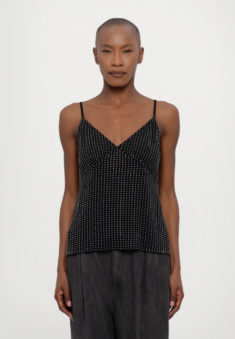 Camiseta negra de tirantes finos, con un patrón de puntos blancos en todo su diseño, con escote en V y una silueta ajustada.