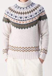 Sweter z dzianiny z wysokim rybnym kołnierzem. Jasnobeżowa baza, zdobiona skomplikowanymi, wielokolorowymi wzorami w odcieniach niebieskiego, zielonego i pomarańczowego wokół karczku.