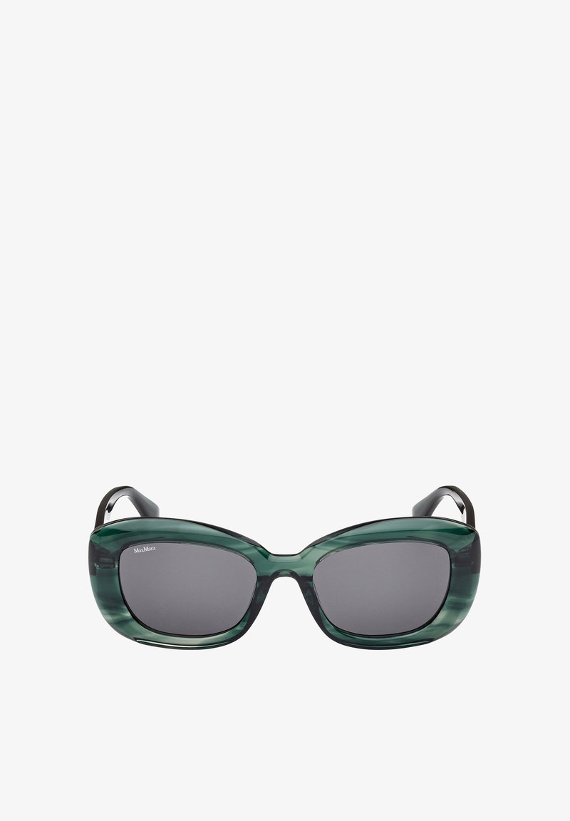 Okulary przeciwsłoneczne typu kocie oko z ciemnoszarymi soczewkami, zielonymi przezroczystymi oprawkami i czarnymi, zwężanymi zausznikami. Charakteryzują się gładką fakturą i odważnym designem.